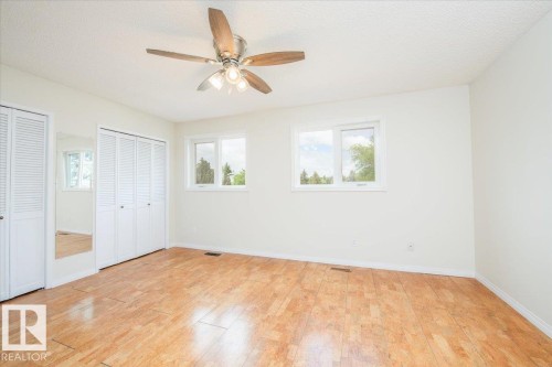 Bright interior space featuring wood-finish flooring, white walls, and a ceiling fan with integrated lighting - 4107 147 Street, Edmonton, AB 