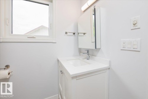 Compact bathroom featuring a white vanity with integrated sink, chrome faucet, and coordinating medicine cabinet - 4107 147 Street, Edmonton, AB 