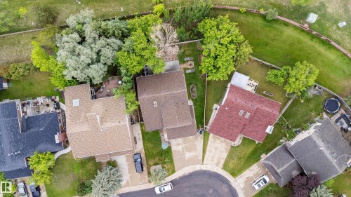 Aerial perspective showcasing a residential property with a brown shingle roof, a concrete driveway, and a spacious green lawn - 4107 147 Street, Edmonton, AB 