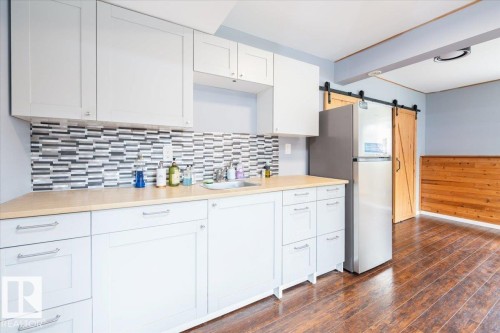 Kitchenette featuring white cabinetry, light wood-finish countertops, and a mosaic tile backsplash - 4107 147 Street, Edmonton, AB 