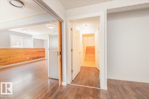 Wood-finish flooring throughout, featuring a natural wood half-wall with integrated lighting in the main area - 4107 147 Street, Edmonton, AB 