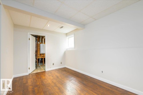 Room featuring wood-finish flooring, white painted walls, and a drop ceiling with recessed lighting - 4107 147 Street, Edmonton, AB 