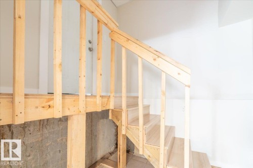 Unfinished wood staircase with balusters leading to an upper level landing with a white door - 4107 147 Street, Edmonton, AB 