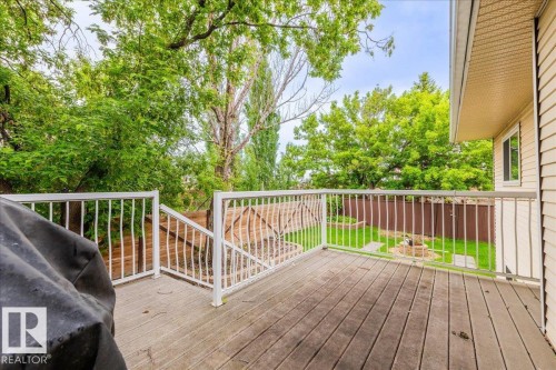 Spacious wood-finish deck with white railings and stairs leading to a fenced backyard - 4107 147 Street, Edmonton, AB 