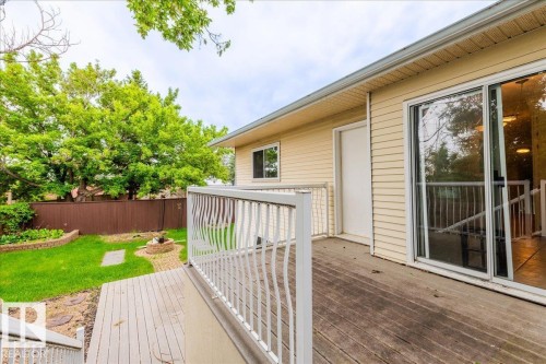 Outdoor wooden deck with white railing featuring steps to a grassy yard - 4107 147 Street, Edmonton, AB 