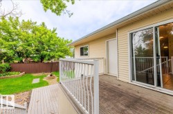Outdoor wooden deck with white railing featuring steps to a grassy yard - 