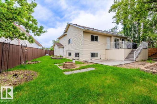 Expansive backyard with a manicured lawn, a raised deck with white railings, and a ground-level patio - 4107 147 Street, Edmonton, AB 
