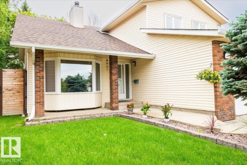 Cream-colored siding exterior with brick accents, featuring a prominent bay window and a covered front entry - 4107 147 Street, Edmonton, AB 