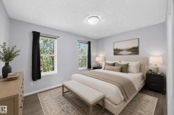 Spacious room featuring wood-finish flooring, light grey walls, and two large windows with white trim - 