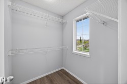 Walk-in closet featuring a window, wire shelving system, light gray wall paint, and wood-finish flooring - 