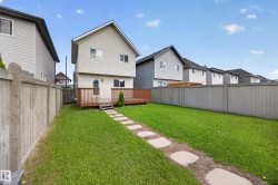 Expansive backyard featuring a manicured lawn, a stone paver pathway, and a large wooden deck - 