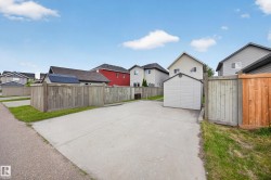 Paved parking area featuring a detached storage shed, full perimeter fencing, and partial grass verge - 