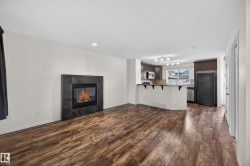 Open-concept room featuring wood-finish flooring, a fireplace with dark tile surround, and recessed lighting - 