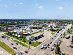 Aerial perspective showcasing a commercial district with multiple retail buildings, a gas station, and ample parking areas - 