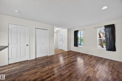 Spacious room with rich wood-finish flooring, recessed ceiling lighting, and multiple windows providing natural illumination - 