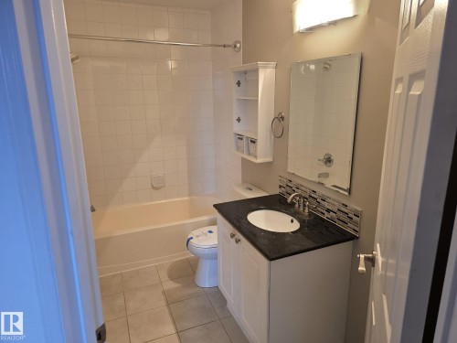 Bathroom featuring a vanity with a dark countertop, white under-mount sink, and contemporary faucet - 35 10331 106 Street, Edmonton, AB 
