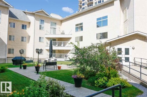 Courtyard space featuring a concrete pathway, manicured lawn, and mature landscaping - 35 10331 106 Street, Edmonton, AB 