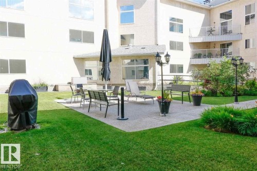 Expansive outdoor patio featuring a concrete surface and surrounding green lawn - 35 10331 106 Street, Edmonton, AB 