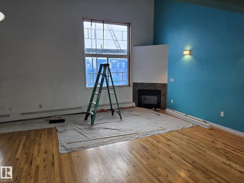 Hardwood flooring spans the interior, complemented by a corner fireplace with a dark tile surround - 35 10331 106 Street, Edmonton, AB 