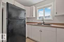 Kitchen featuring white cabinetry, a double basin sink with a matte black faucet, and a large window - 
