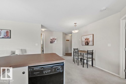 Kitchen island with laminate countertop, integrated black dishwasher, and white cabinetry - 232 4309 33 Street, Stony Plain, AB 