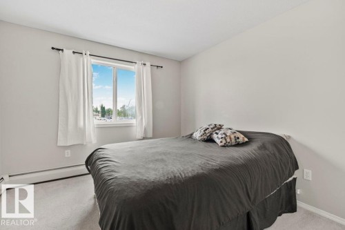 Carpeted room featuring a double-pane window, baseboard heating, and light-toned walls - 232 4309 33 Street, Stony Plain, AB 
