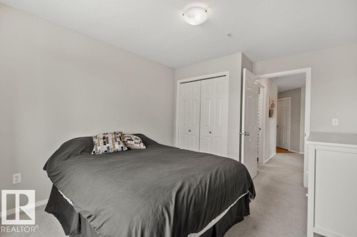 Carpeted room featuring light gray walls, a flush-mount ceiling light fixture, and white bi-fold closet doors - 232 4309 33 Street, Stony Plain, AB 