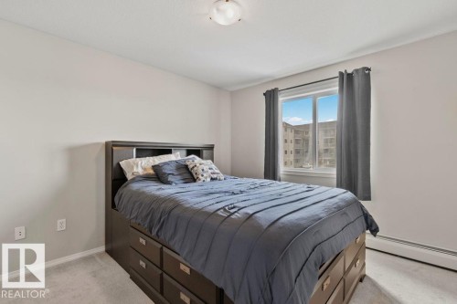 Neutral-toned room featuring a window with an exterior building visible, overhead lighting, and baseboard heating - 232 4309 33 Street, Stony Plain, AB 