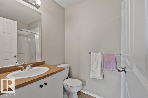 Bathroom featuring a white vanity with a tan countertop and an integrated sink, a chrome faucet, and a wall-mounted mirror - 232 4309 33 Street, Stony Plain, AB 