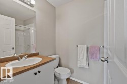 Bathroom featuring a white vanity with a tan countertop and an integrated sink, a chrome faucet, and a wall-mounted mirror - 