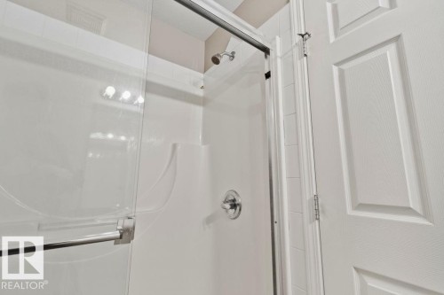Shower enclosure featuring clear glass sliding doors and a chrome handle - 232 4309 33 Street, Stony Plain, AB 
