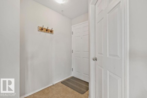 Entryway with light neutral wall paint, tiled flooring, and a white paneled door - 232 4309 33 Street, Stony Plain, AB 