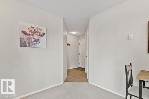 Open hallway with light gray walls, white baseboards, and neutral carpet flooring - 232 4309 33 Street, Stony Plain, AB 