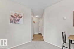 Open hallway with light gray walls, white baseboards, and neutral carpet flooring - 