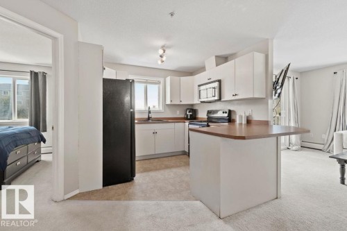 Kitchen featuring white cabinetry, dark countertops, and stainless steel appliances - 232 4309 33 Street, Stony Plain, AB 