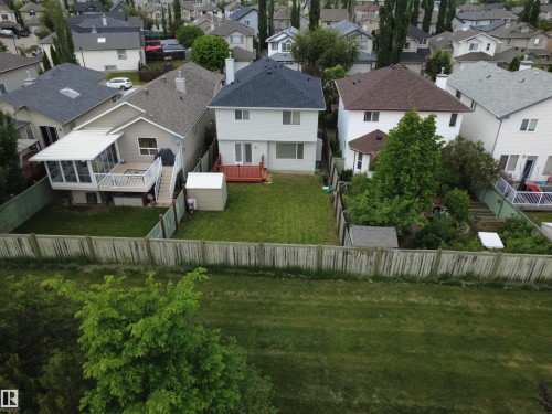 Rear exterior featuring a spacious green lawn, wood deck, and a shed - 21113 92A Avenue Nw, Edmonton, AB 