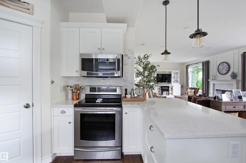 Kitchen featuring white cabinetry, stainless steel appliances, a white subway tile backsplash, and a large central island with a light-colored countertop - 34 Falcon Road, Cold Lake, AB 