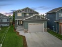 Contemporary two-story home featuring dark green siding, a prominent attached garage with a concrete driveway, and a stone accent facade - 34 Falcon Road, Cold Lake, AB 