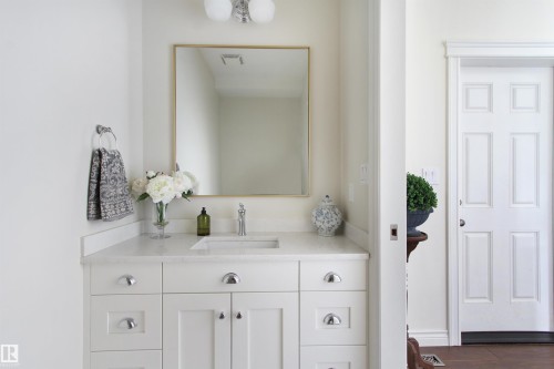 White shaker-style vanity with polished chrome hardware, a light-toned countertop, and an undermount sink - 34 Falcon Road, Cold Lake, AB 