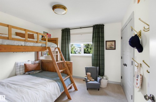 Room featuring a wooden bunk bed with integrated ladder, light carpet flooring, and a window with dark curtains - 34 Falcon Road, Cold Lake, AB 