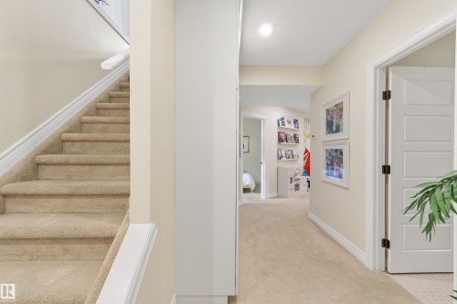 Carpeted staircase with white handrail and baseboards, complemented by a hallway featuring a recessed light and a paneled door - 34 Falcon Road, Cold Lake, AB 
