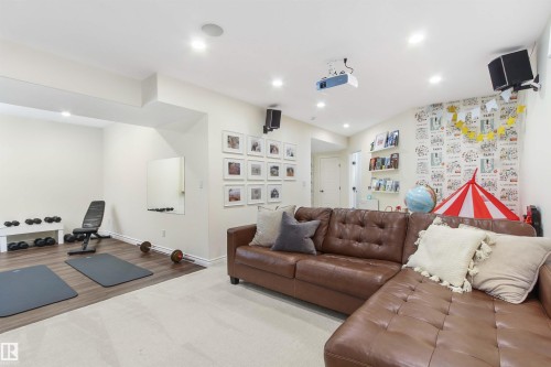 Expansive recreation room featuring recessed lighting, a dedicated exercise area with wood-finish flooring, a wall-mounted projector, built-in shelving, and a combination of carpet and hard surface flooring - 34 Falcon Road, Cold Lake, AB 