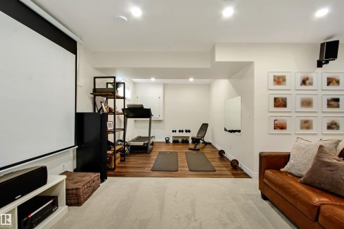 Finished basement space featuring recessed lighting, carpeted and wood-finish flooring, a wall-mounted projection screen, and a dedicated fitness area - 34 Falcon Road, Cold Lake, AB 