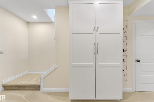Built-in white cabinetry with brushed nickel hardware, neutral-toned walls, recessed lighting, carpeted staircase, and white trim throughout - 34 Falcon Road, Cold Lake, AB 