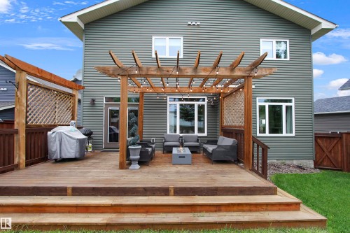 Multi-level wood deck featuring a pergola, privacy lattice, and steps leading to a grassed area - 34 Falcon Road, Cold Lake, AB 