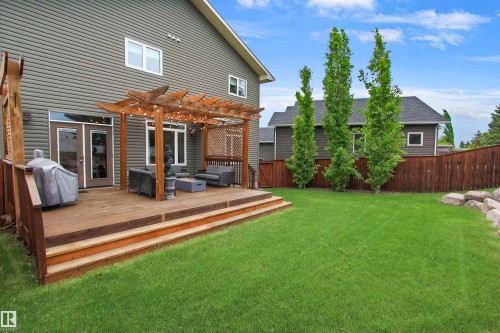 Expansive backyard featuring a multi-level wood deck with a pergola, string lighting, and direct access through double patio doors - 34 Falcon Road, Cold Lake, AB 