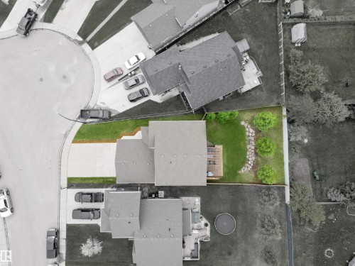 Expansive backyard featuring a green lawn, wood deck, and a rock garden with plantings - 34 Falcon Road, Cold Lake, AB 