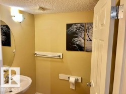 Pedestal sink with chrome faucet, complemented by an oval mirror and wall-mounted light fixture - 