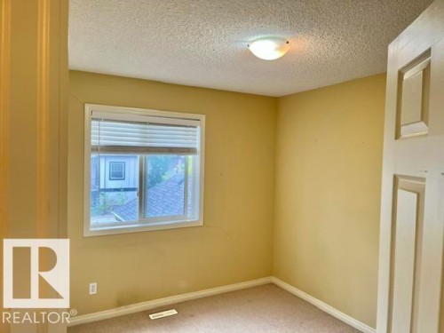 Room featuring a single window with blinds, carpeted flooring, and a flush-mount ceiling light fixture - 1 5281 Terwillegar Boulevard, Edmonton, AB 