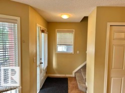 Foyer featuring a paneled entry door with sidelights, tiled flooring, an overhead flush-mount light fixture, and carpeted stairs - 
